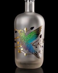 Gravure d'un colibri sur une bouteille satin&eacute;e et d&eacute;cor&eacute;e d'un marquage &agrave; chaud, multi couleurs fondues. R&eacute;alisation MSV.